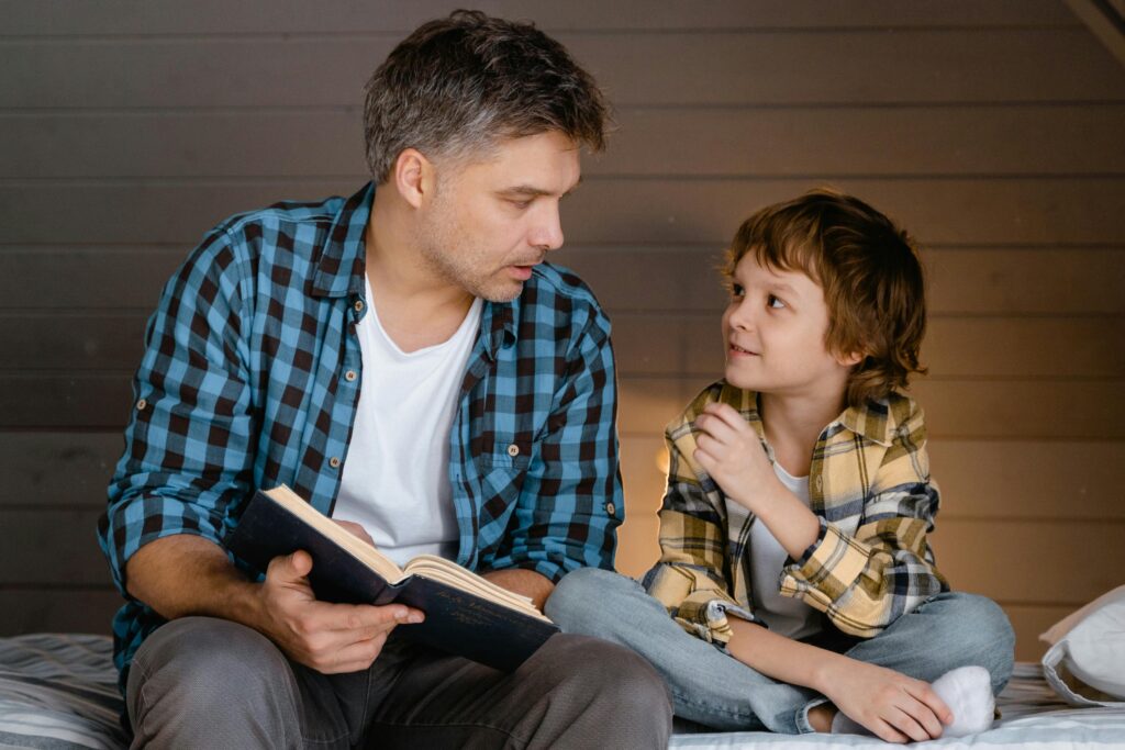 A father and son share a bonding moment reading together indoors, fostering family connection.